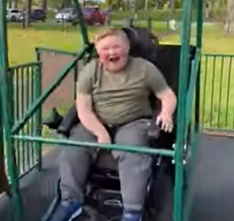 Boy smiles in a playground on a swing