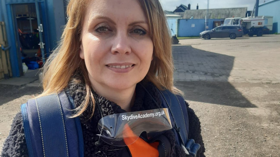 A women with skydiving googles smiles at the cameera