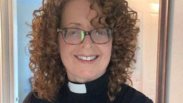 a vicar smiles at the camera