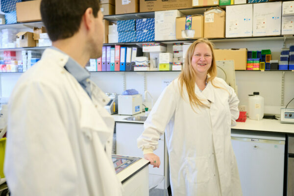 Two smiling scientists talk in a lab