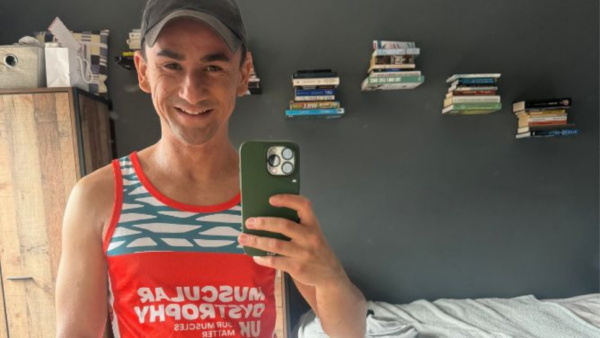 A man takes a selfie in a bedroom wearing MDUK branded sports top
