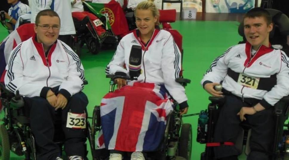 Three paralympians with a Team GB flag pose for the camera