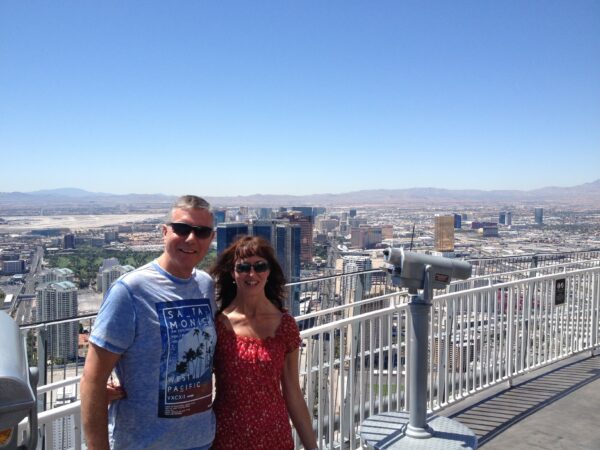 A woman and a man standing high up on a clear day. A city is inn the background