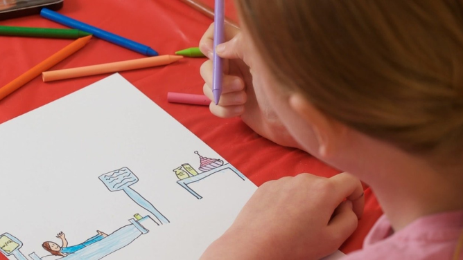 A girl draws with crayons a hospital room