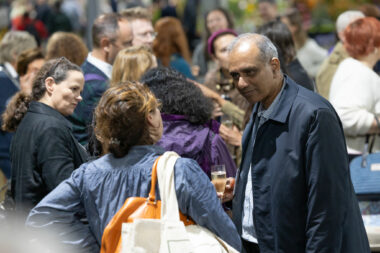 A man and women talk in a sea of other people.