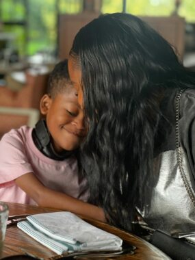 A smiling young boy is embraced by a women affectionetly