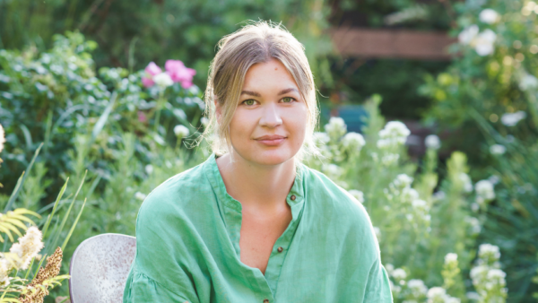 A women poses in a whimscial garden wearing a green floaty top
