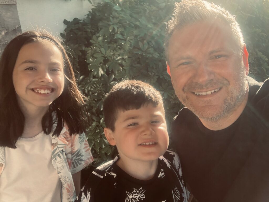 A dad with his two young children - one is a boy and the other is a girl