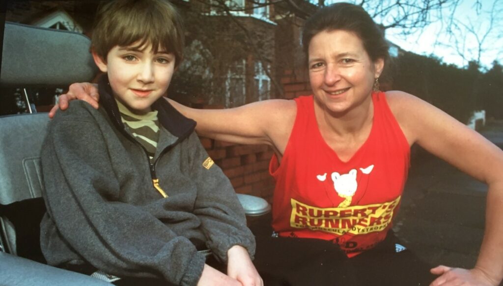 A lady with her arm round a boy in a wheelchair