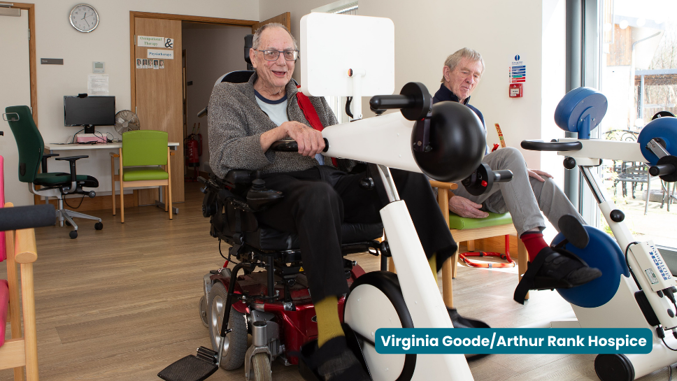 An elderly man in a wheelchair with feet on pedals and hands on a handlebar