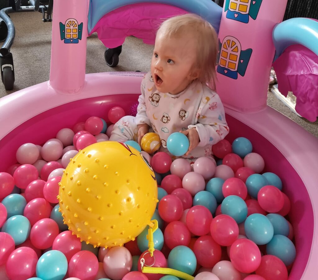 A baby in a pink castle ball pit