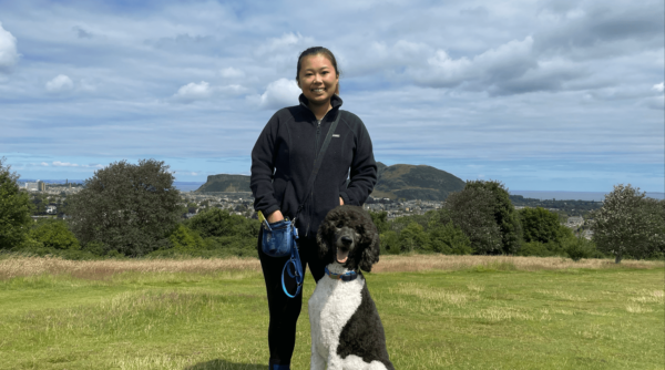 A photo of a lady holding a dog in a green field