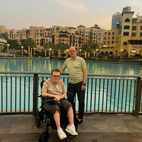 Ben in a wheelchair smiling, the Burj Khalifa is in the background.