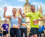 A pair of runners smile while waving at the camera during the Cambridge 10k.
