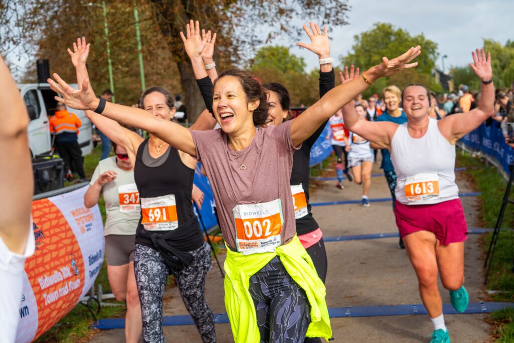 A group of runners celebrate with their arms in the air during the Cambridge 10k.