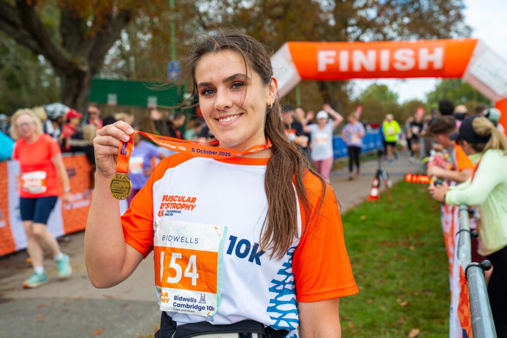 A runner poses with their medal after finishing the Cambridge 10k.
