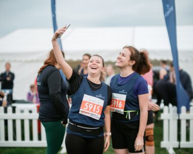Two girls laugh while taking a selfie picture.