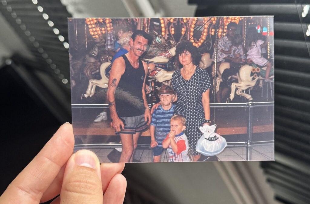 A hand is holding a photograph of a family