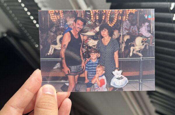 A hand is holding a photograph of a family