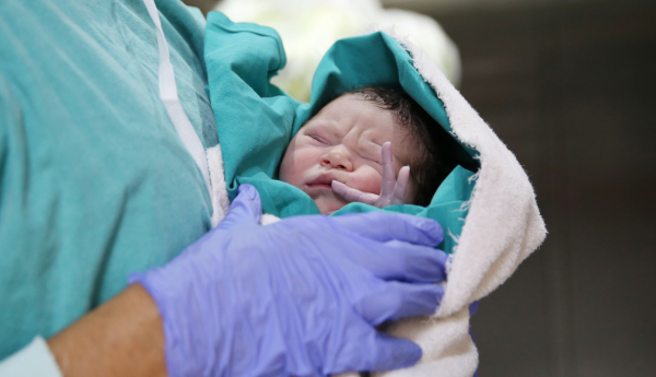 Newborn baby being held by a healthcare professional shortly after birth.