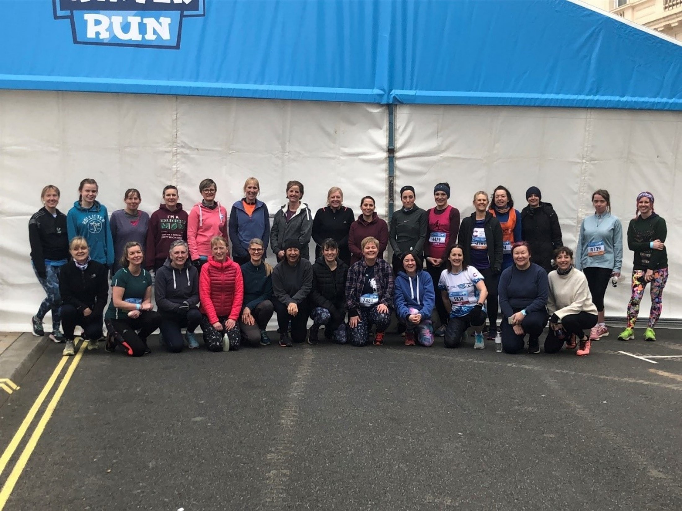 A group picture of runners all gathered in front of a tent