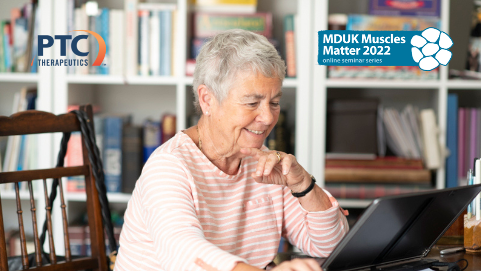 An image of a lady from the side. She is sat in front of a bookcase, smiling whilst on her laptop. This image is overlayed by the Muscles Matter logo and PTC therapeutics logo