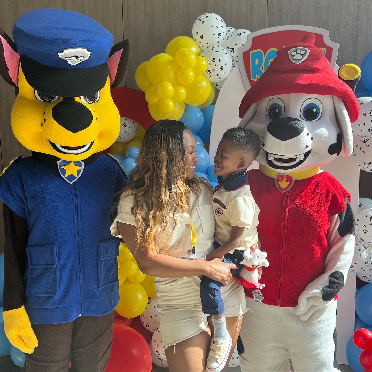 Tiffany and Roman looking at each other, smiling. They are stood with 2 characters from Paw Patrol.