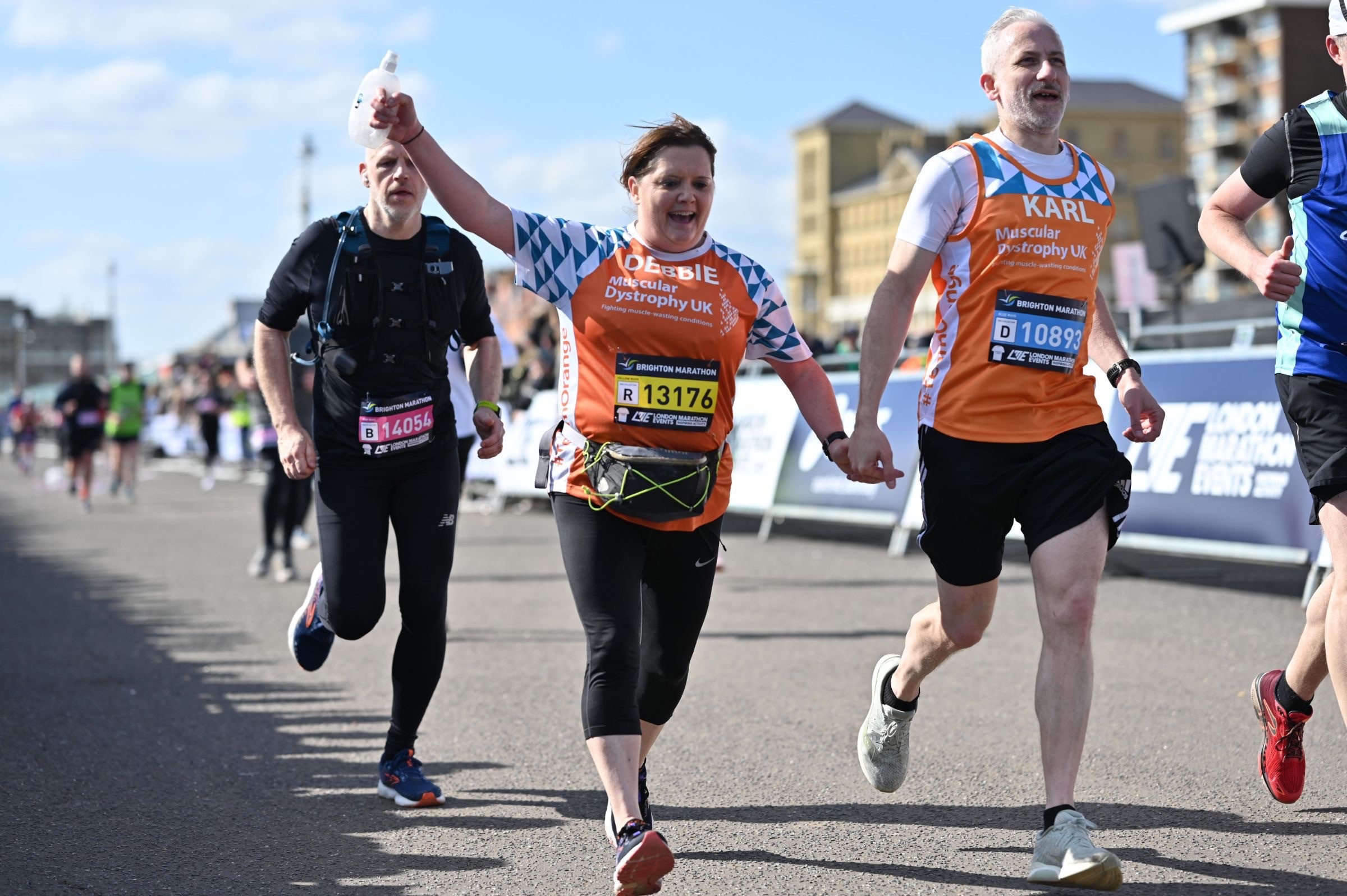 Debbie and Karl running, wearing their Team Orange jerseys at the Brighton Marathon