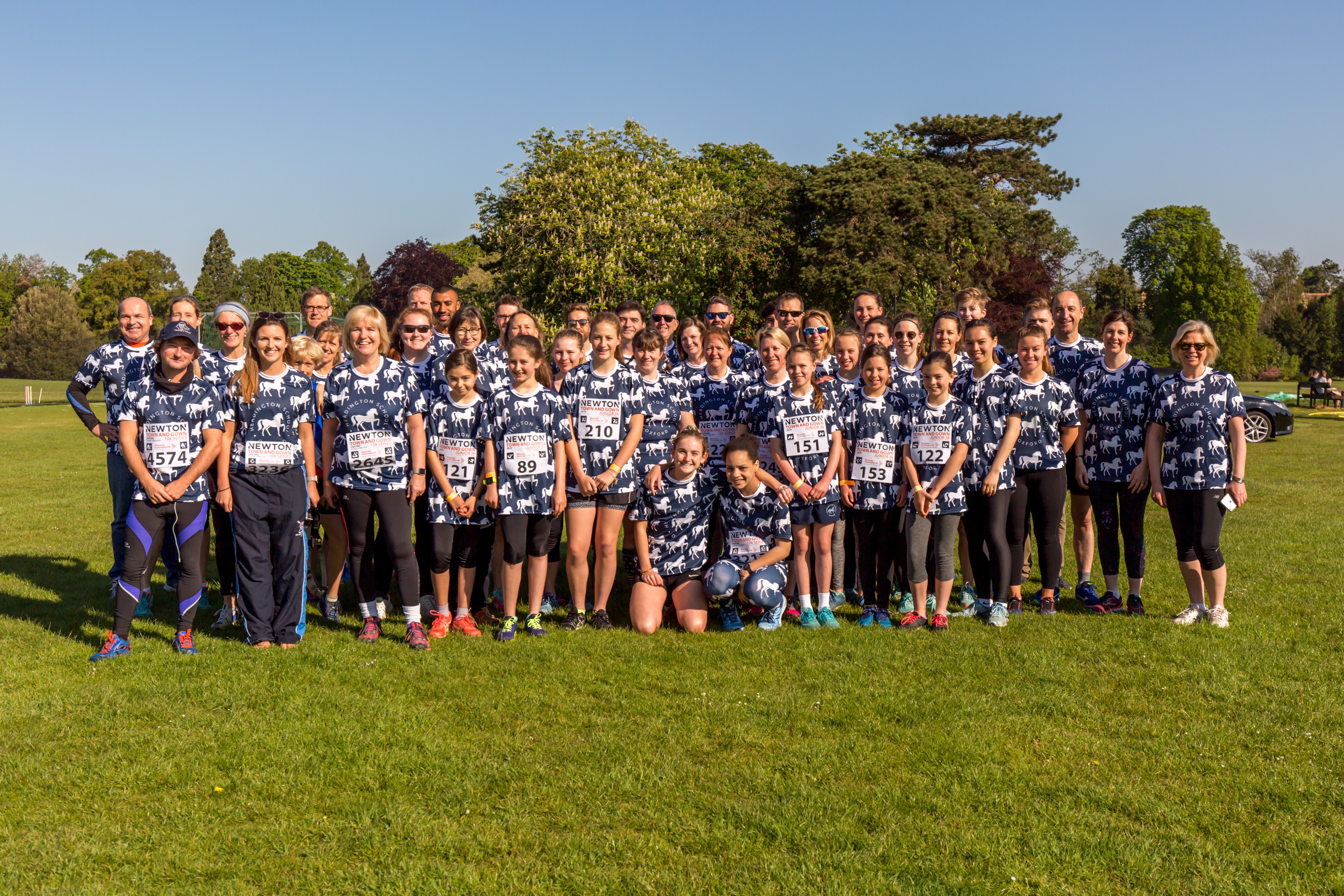 Group picture of Headington School in their running hear, all stood in the park