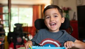 A young boy who has SMA smiles while sat in his wheelchair