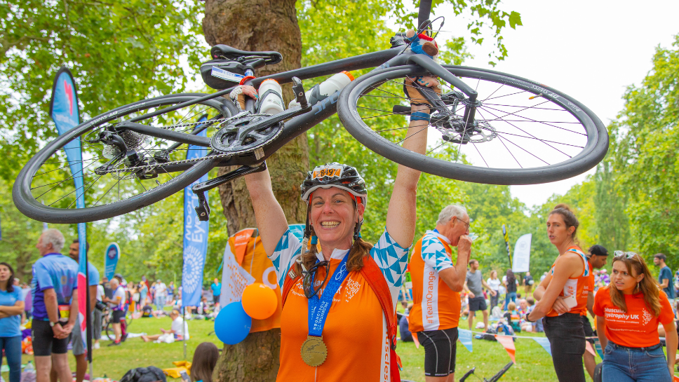Woman holding bike in air in celebration after completing RideLondon