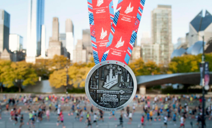 Chicago Marathon medal with people running in the background at the event
