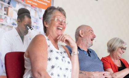 Two women and a man laughing while seated together at an MDUK Muscle Group.