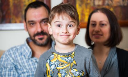 Young boy who has Duchenne muscular dystrophy smiles with his parents