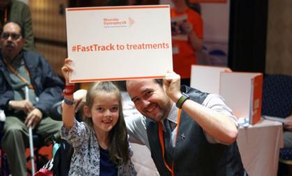 young girl and adult male holding a sign that says "FastTrack to treatment"