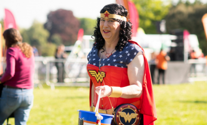 Phil Grant dressed as wonder woman holding donation bucket