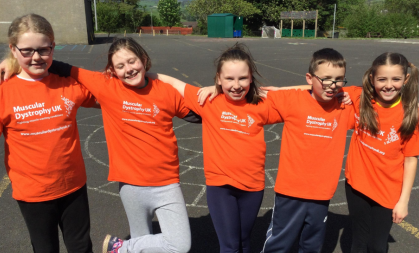 Winter Logue with Rhys and 3 other friends wearing orange MDUK branded t-shirts, standing in a row with their arms round each other
