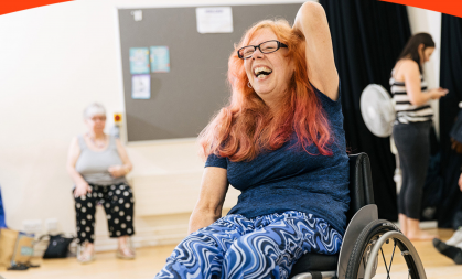 A woman laughing during a wheelchair dance class. 