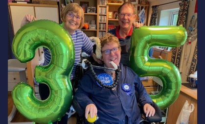 Angela, Brian and their son Jonathan celebrate his 35 birthday with green number balloons. 