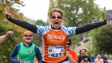 A Team Orange runner jumping with their arms in the air during their run