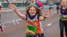 A Team Orange GNR runner smiling, with her arms out, running towards the camera
