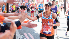 A Team Orange runner smiling and high-fiving as they run past