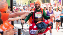 A Team Orange runner in a gnome costume, smiling as they run past