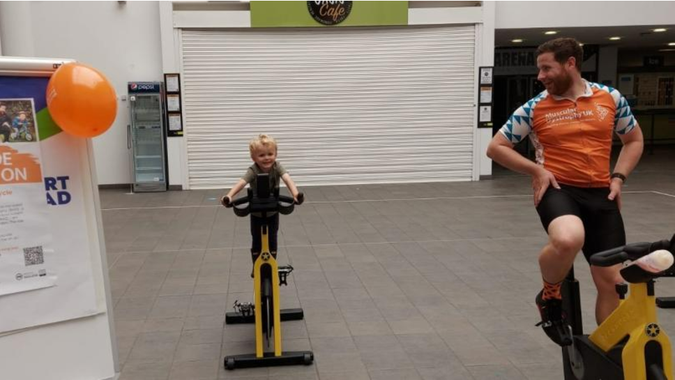 Paul Murphy and toddler Henry Robson on exercise bikes