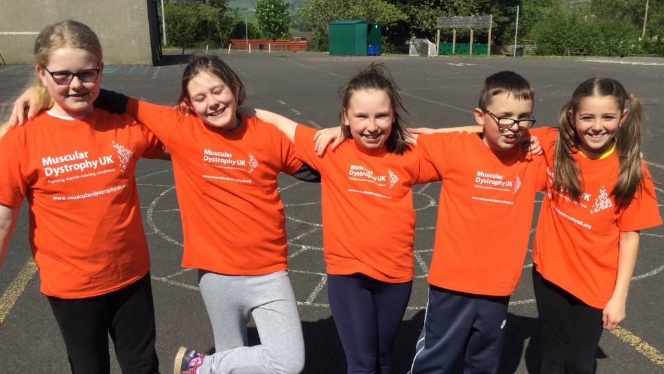 Winter Logue with Rhys and 3 other friends wearing orange MDUK branded t-shirts, standing in a row with their arms round each other